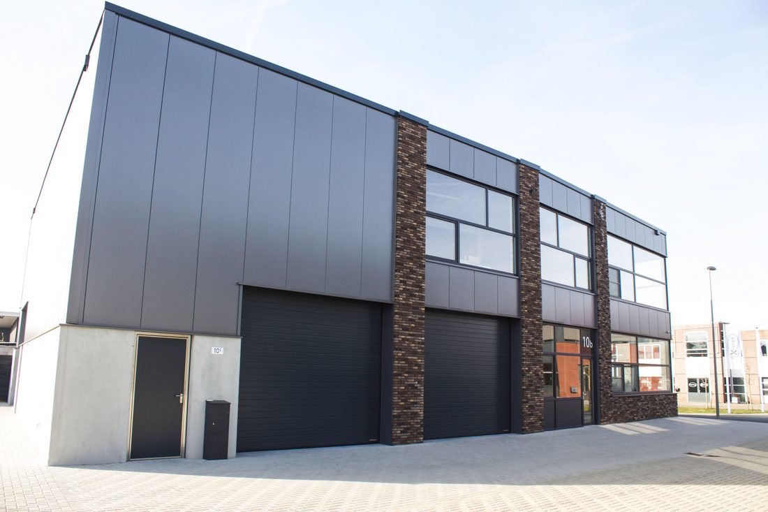 Nieuwbouw bedrijfsunits met antracieten overheaddeuren en metselwerk