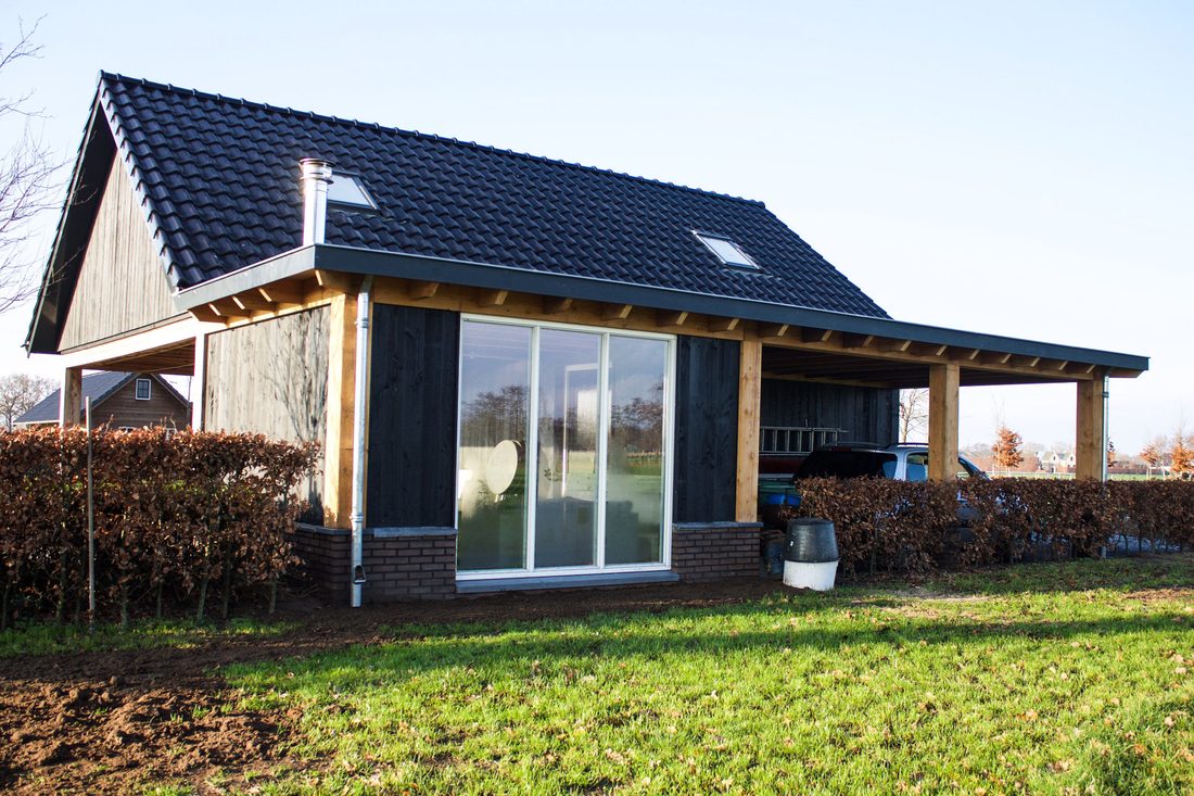 Verbouw: bijgebouw in zwart hout met douglas overkapping, schuifpui en gebakken dakpannen