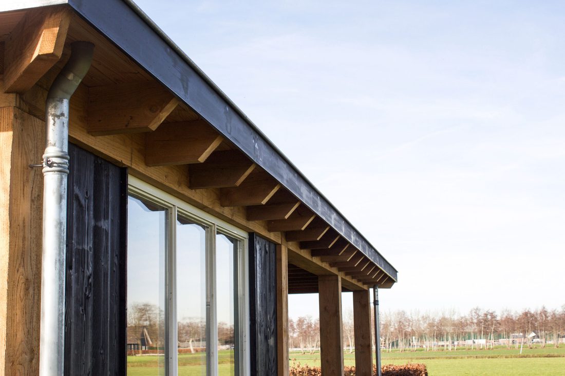 Zijgevel van een bijgebouw met schuifpui en doorlopende overkapping