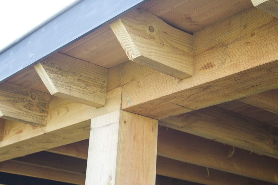 Detail van de houtverbinding tussen douglas balken en staander van een overkapping